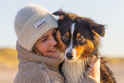 Ferienhaus mit Hund in Dänemark – Urlauberin mit Hund bei einem Strandspaziergang